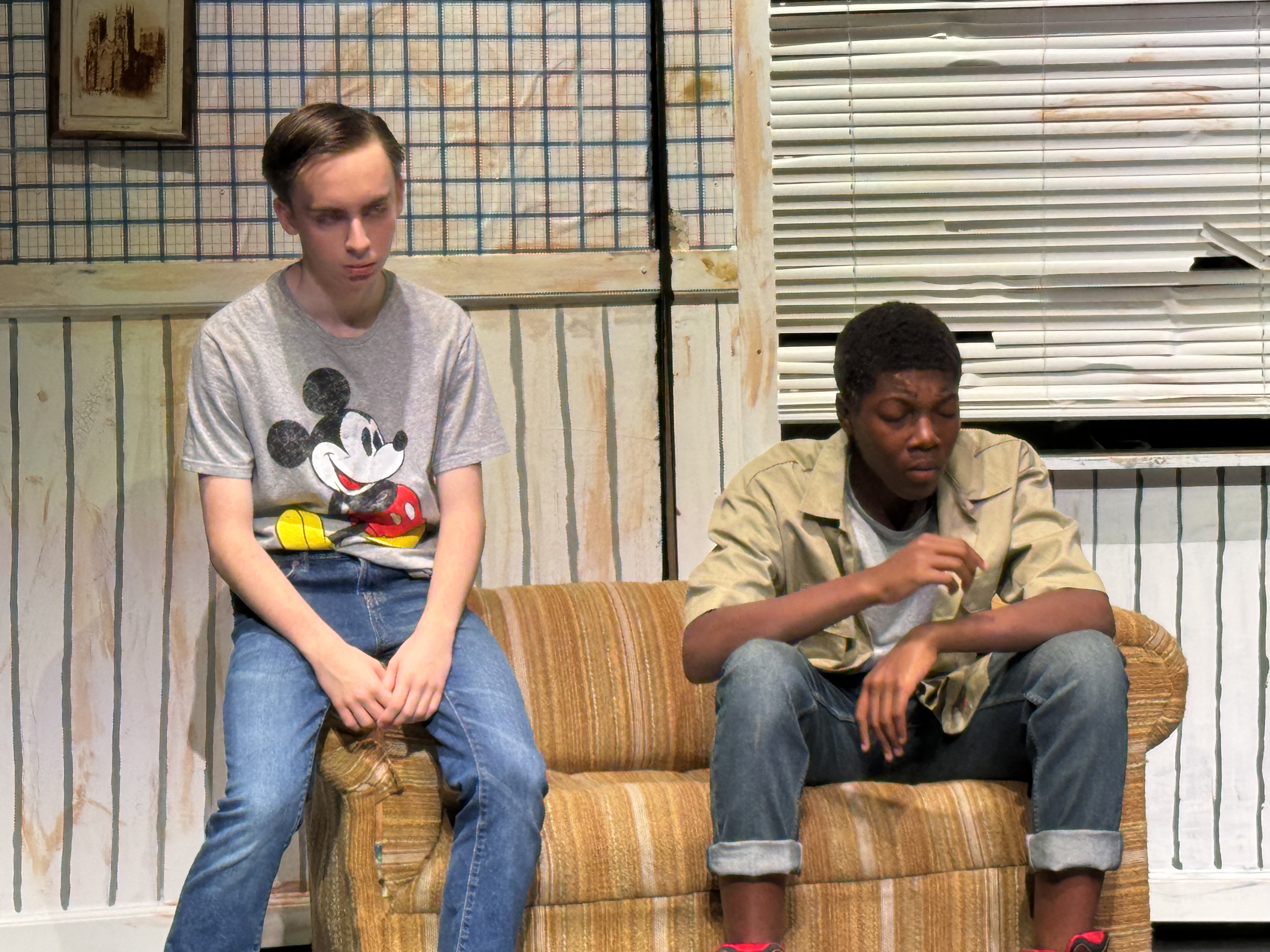 Two-character scene on a worn couch